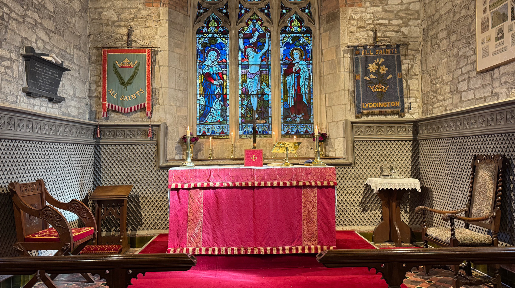 Church altar with stained glass window and red altar cloth inside historic stone church