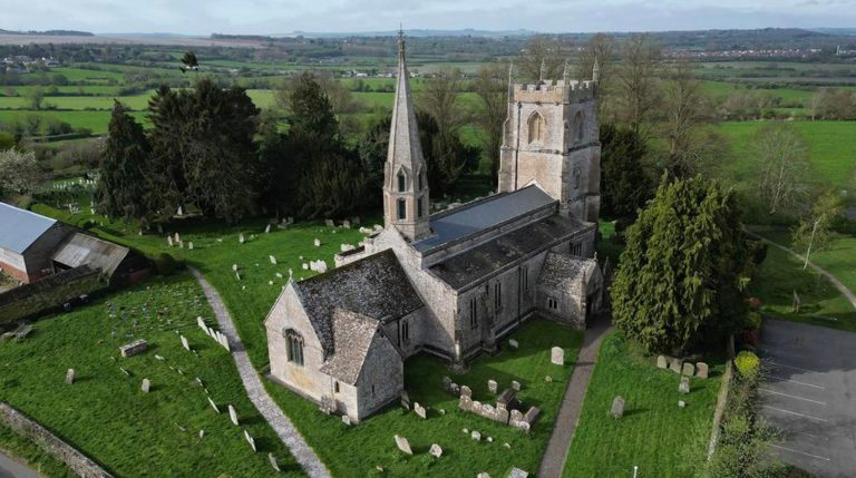 Aerial view of historic English village church with surrounding countryside