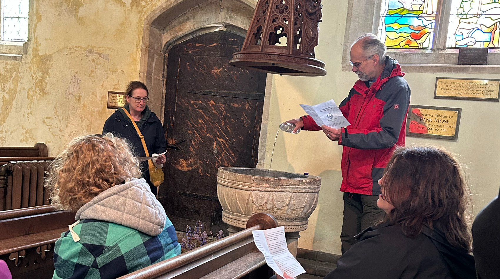 Church congregation gathered around stone font during baptism or blessing service