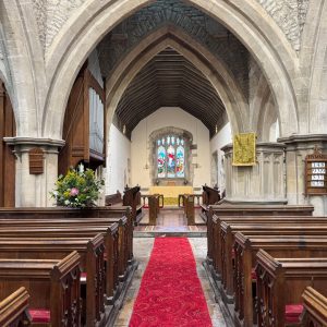 Interior of a traditional church with wooden pews, stone arches, red aisle carpet and altar