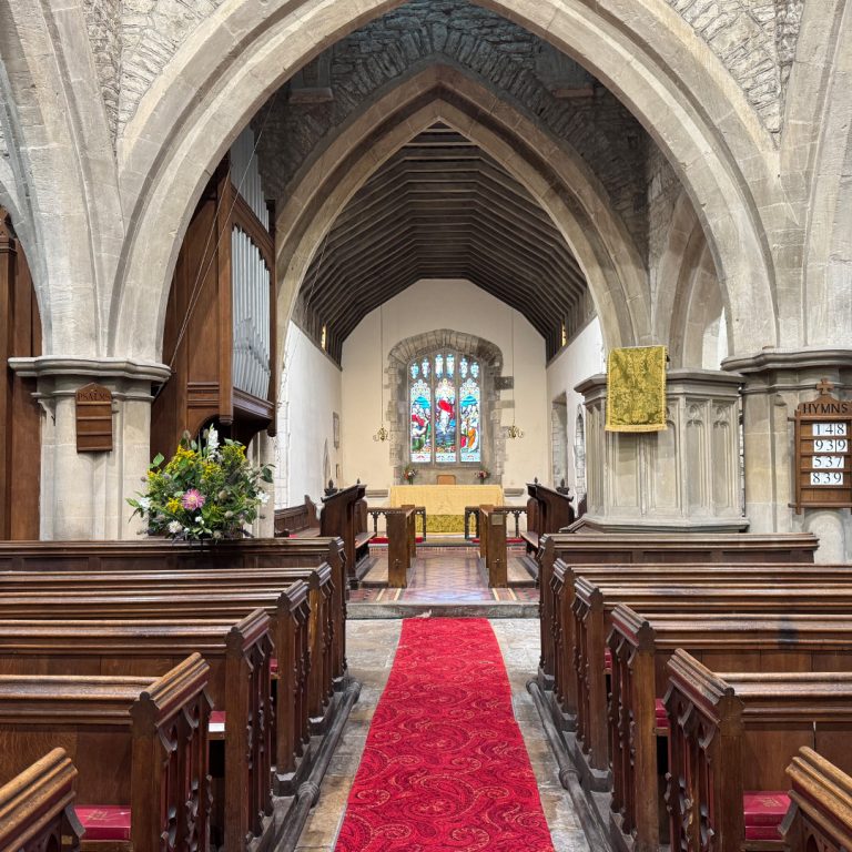 Interior of a traditional church with wooden pews, stone arches, red aisle carpet and altar