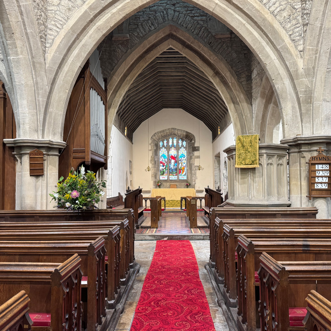 Interior of a traditional church with wooden pews, stone arches, red aisle carpet and altar